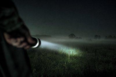 Feldweg mit Taschenlampenlicht bei Nacht