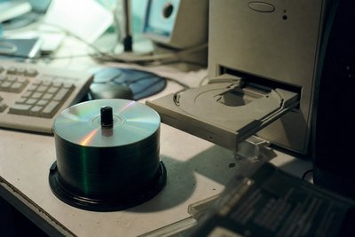 Spindel gebrannter Rohlinge neben einem offenen CD-Laufwerk